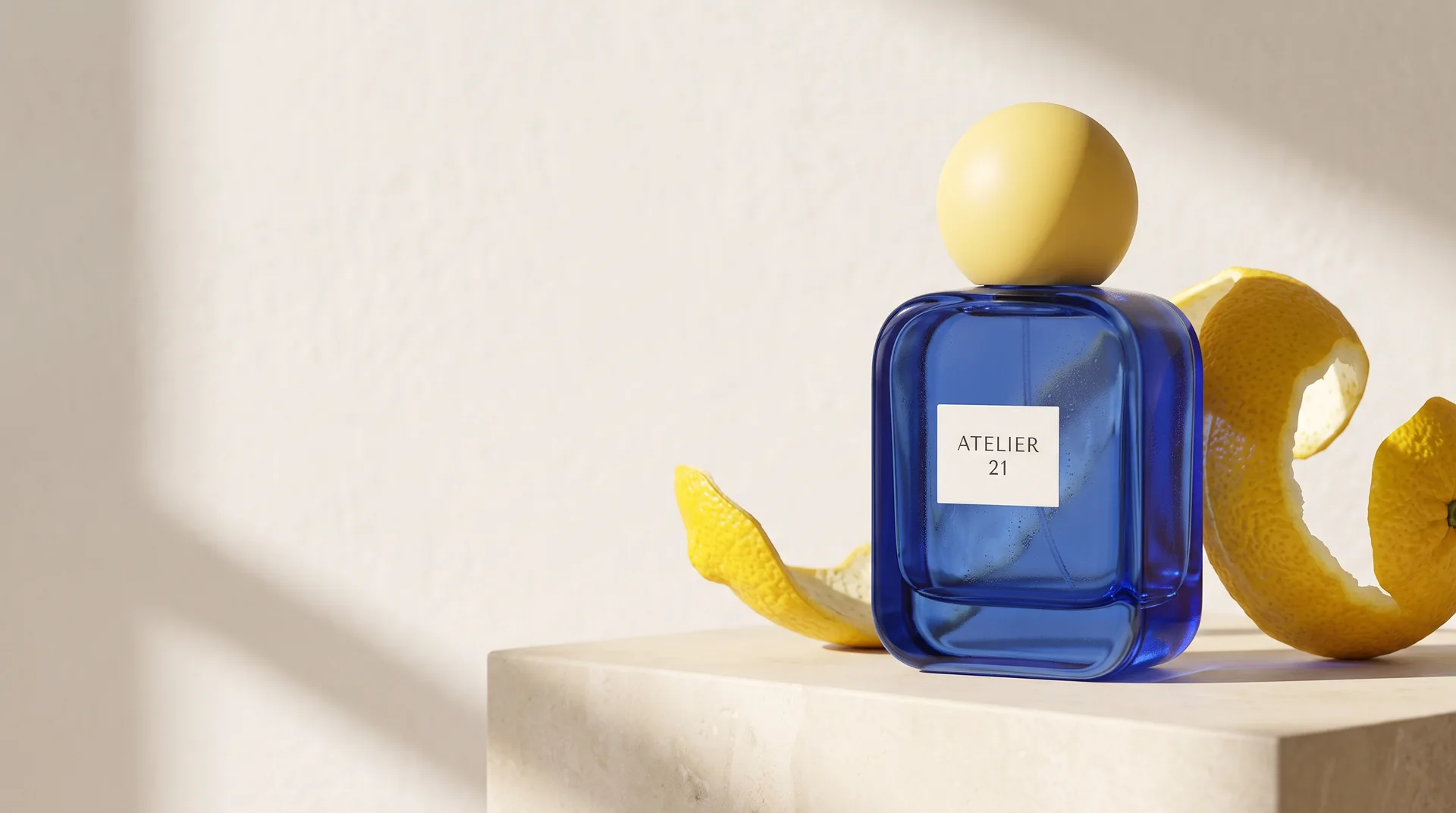 Cobalt-blue perfume bottle with a yellow spherical cap beside sculptural lemon peel on pale stone.